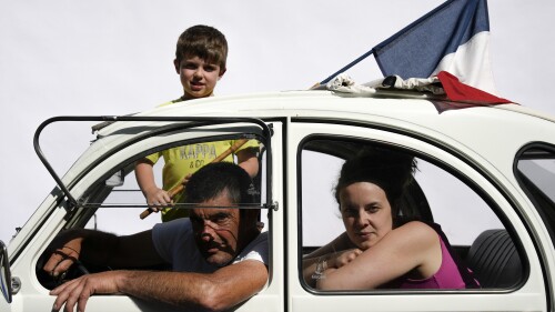 Philippe Planet poses for a portrait with his daughter Laurine and grandson Evan Bousset in their tricolour Citroen 2CV during the tenth stage of the Tour de France cycling race over 167 kilometers (104 miles) with start in Vulcania and finish in Issoire, France, Tuesday, July 11, 2023. (AP Photo/Daniel Cole)