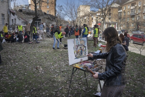 A student of Kyiv State Arts Academy paints as other students and volunteers clear the rubble after the Academy was partly ruined during the Russian missile attack a few days ago in Kyiv, Ukraine, Saturday, March 30, 2024. (AP Photo/Efrem Lukatsky)
