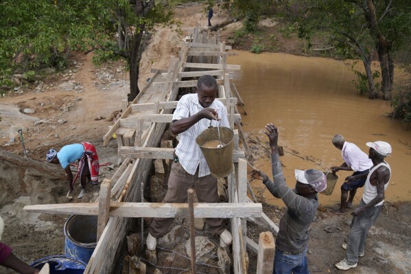 Residents in Machakos County, Kenya, construct a sand dam on Thursday, Feb. 29, 2024. Building sand dams, a structure for harvesting water from seasonal rivers, helps minimize water loss through evaporation and recharges groundwater. (AP Photo/Brian Inganga)