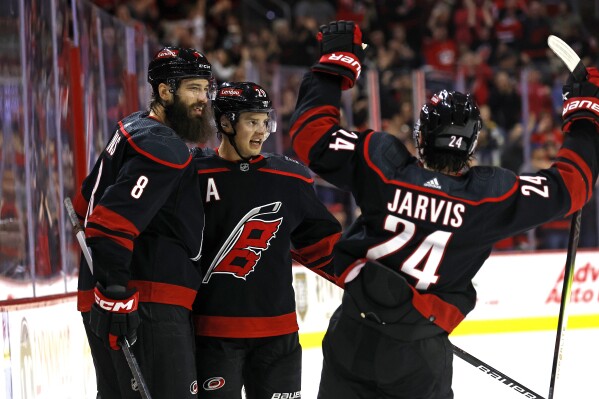 Carolina Hurricanes' Sebastian Aho, center, celebrates his goal with teammates Brent Burns (8) and Seth Jarvis (24) during the second period of an NHL hockey game against the Pittsburgh Penguins in Raleigh, N.C., Saturday, Nov. 18, 2023. (AP Photo/Karl B DeBlaker)