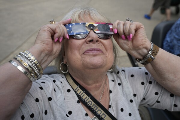 Karen Haun, of Lantana, Texas, uses solar glasses to watch beginning of a solar eclipse, as seen from Fort Worth, Texas, Monday, April 8, 2024. (AP Photo/LM Otero)