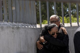 Lorena Villavicencio, sister of slain presidential candidate Fernando Villavicencio, embraces her husband outside the morgue where her brother's body is being held, in Quito, Ecuador, Thursday, Aug. 10, 2023. Villavicencio was shot and killed as he was leaving a campaign rally at a school in the Ecuadorian capital, less than two weeks before the Aug. 20 presidential election. (AP Photo/Carlos Noriega)