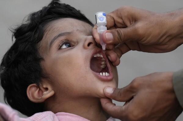 A health worker administers a polio vaccine to a child at a railway station in Karachi, Pakistan, Monday, Sept 18, 2023. Authorities in one province of Pakistan are turning to a controversial new tactic in the decades-long initiative to wipe out polio: prison. Earlier this month, the government in Sindh introduced a law that threatens to imprison parents for up to one month if they fail to get their children immunized against polio or eight other common diseases. (AP Photo/Fareed Khan)