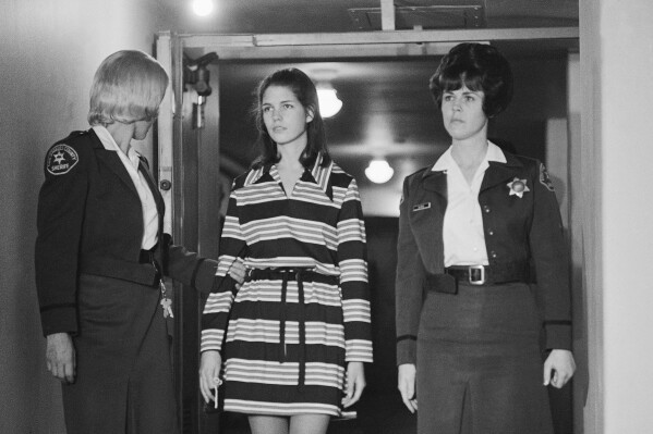 FILE - Leslie Van Houten, 19, a member of Charles Manson's "family" who is charged with the murders of Leno and Rosemary LaBianca, is escorted by two deputy sheriffs as she leaves the courtroom in Los Angeles, Dec. 19, 1969, after a brief hearing. Van Houten has been released from a California prison after serving 53 years for two infamous murders. The California Department of Corrections and Rehabilitation said Tuesday, July 11, 2023, that Van Houten "was released to parole supervision." (AP Photo/George Brich, File)