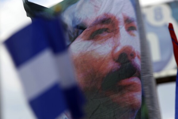 FILE - A banner emblazoned with an image of Nicaragua's President Daniel Ortega is waved by a supporter in Managua, Nicaragua, April 30, 2018. The U.S. State Department on Saturday, Aug. 19, 2023, imposed visa restrictions on 100 more Nicaraguan officials for their role in supporting the Ortega regime. (AP Photo/Alfredo Zuniga, File)