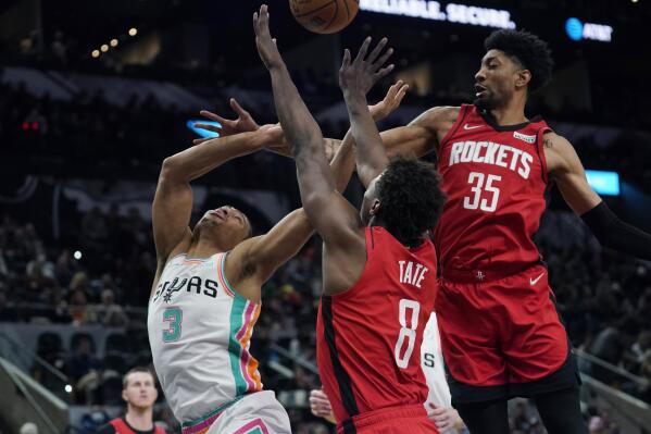 San Antonio Spurs forward Keldon Johnson (3) is fouled as he drives to the basket against Houston Rockets forward Jae'Sean Tate (8) and center Christian Wood (35) during the second half of an NBA basketball game Friday, Feb. 4, 2022, in San Antonio. (AP Photo/Eric Gay)