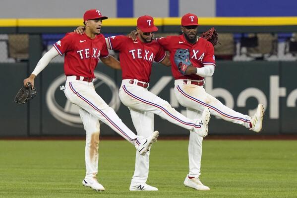 Texas Rangers outfielders Adolis Garcia, right, Bubba Thompson, center, and Leody Taveras dance together after the final out of a baseball game against the Detroit Tigers in Arlington, Texas, Friday, Aug. 26, 2022. (AP Photo/LM Otero)