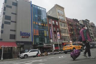 A six story glass facade building, second from left, is believed to be the site of a foreign police outpost for China in New York's Chinatown, Monday April 17, 2023. Justice Department officials say two men have been arrested on charges that they helped establish a secret police outpost in New York City on behalf of the Chinese government. (AP Photo/Bebeto Matthews)