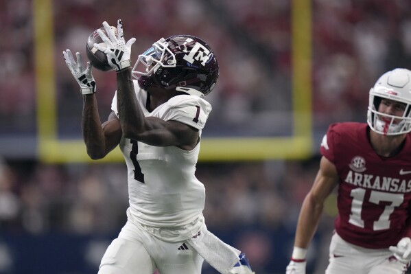 Texas A&M wide receiver Evan Stewart (1) catches a touchdown pass in front of Arkansas defensive back Hudson Clark (17) during the first half of an NCAA college football game, Saturday, Sept. 30, 2023, in Arlington, Texas. (AP Photo/LM Otero)