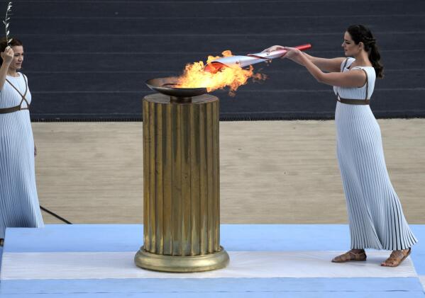 FILE - Greek actress Xanthi Georgiou, playing the role of High Priestess, lights the torch with the flame during the Olympic flame handover ceremony at Panathinean stadium in Athens, Greece, Tuesday, Oct. 19, 2021. Instead of arriving overland, the symbolic flame alighting the Paris 2024 Games will take to the seas from its birthplace in Greece, arriving aboard a three-masted tall ship in the French port of Marseille. Paris 2024 organizers announced the flame's journey Friday Feb.3, 2023 at City Hall in Marseille, a former Greek colony founded 2,600 years ago. (AP Photo/Petros Giannakouris, File)