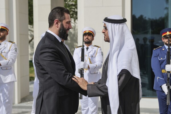 This photo released by the official Syrian news agency SANA, shows United Arab Emirates President Sheikh Mohammed bin Zayed Al Nahyan, right, welcoming Syrian President Ahmad al-Sharaa in Abu Dhabi, United Arab Emirates, Sunday, April 13, 2025. (SANA via AP)