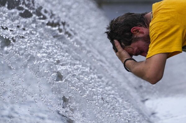 A man cools off at a fountain during a sunny day in Belgrade, Serbia, Thursday, July 13, 2023. (AP Photo/Darko Vojinovic)