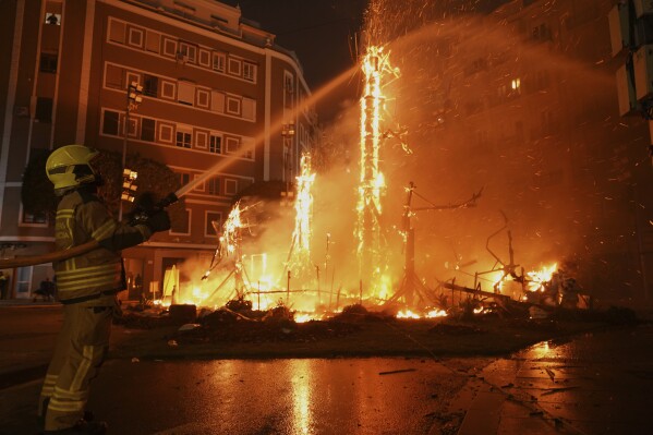 Firefighters put out the remains of the fires in which cardboard sculptures known as "Ninots" burned during the Fallas festival in Valencia, Spain, on Wednesday, March 19, 2025.  (AP Photo/Alberto Saiz)