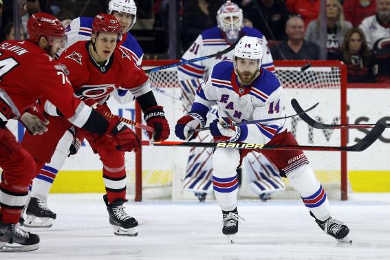 New York Rangers' Tyler Motte (14) clears the puck as Carolina Hurricanes' Jesse Puljujarvi (13) and Jaccob Slavin (74) look on during the first period of an NHL hockey game in Raleigh, N.C., Thursday, March 23, 2023. (AP Photo/Karl B DeBlaker)