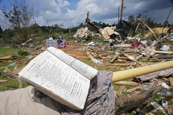 FILE - A prayer book rests on a parking barrier, June 19, 2023, among the debris from an apparent tornado that swept through Louin, Miss., the night before. Mississippi Gov. Tate Reeves has requested financial assistance from the federal government for 16 counties impacted by tornadoes and damaging storms that swept across the state over a five-day period in June, he announced Monday, July 24. (AP Photo/Rogelio V. Solis, File)