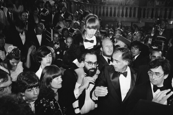 FILE - American director Francis Ford Coppola, center, carries his daughter Sofia, 8, through the crowd after the formal presentation of the U.S. film "Apocalypse Now", at the Cannes International Film Festival in France on May 19, 1979. His son Gian Carlo, 15, and his wife Ellie are left. Coppola is back at Cannes with his latest film "Megalopolis." (AP Photo/Jean-Jacques Levy, File)