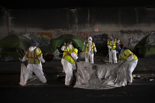 Los Angeles city employees clean up a homeless encampment to relocate homeless individuals into temporary housing as part of Los Angeles Mayor Karen Bass' Inside Safe program in Los Angeles, Tuesday, Oct. 24, 2023. (AP Photo/Jae C. Hong)