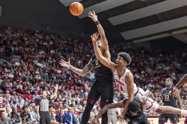 Texas A&M guard Jace Carter (0) and Alabama forward Mohamed Wague (11) chase a loose ball during the first half of an NCAA college basketball game, Saturday, Feb. 17, 2024, in Tuscaloosa, Ala. Texas A&M guard Wade Taylor IV (4) is pictured under Wague. (AP Photo/Vasha Hunt)