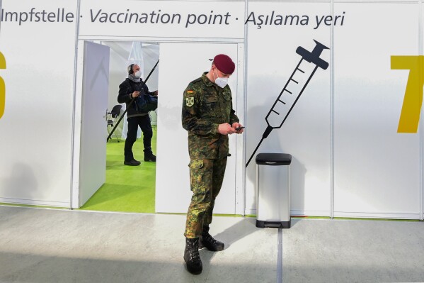 FILE - A soldier of the German Armed Forces Bundeswehr stands inside a new vaccination centre at the former Tempelhof airport in Berlin, Germany, before its opening on Monday, March 8, 2021. Germany has scrapped a requirement for its military servicepeople to be vaccinated against COVID-19. Members of the German military, the Bundeswehr, are required to get vaccinations against a number of diseases — including measles, mumps and flu. COVID-19 was added to the list in November 2021, meaning that anyone who refused to get vaccinated against it could face disciplinary measures. (Tobias Schwarz / Pool via AP, File)