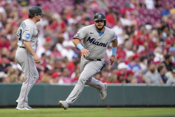 Miami Marlins' Jake Burger, right, rounds third on the way to scoring on a Joey Wendle double against the Cincinnati Reds during the second inning of a baseball gameTuesday, Aug. 8, 2023, in Cincinnati. (AP Photo/Jeff Dean)