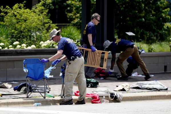 Members of the FBI's evidence response team remove personal belongings one day after a mass shooting in downtown Highland Park, Ill., Tuesday, July 5, 2022. A shooter fired on an Independence Day parade from a rooftop spraying the crowd with gunshots initially mistaken for fireworks before hundreds of panicked revelers of all ages fled in terror. (AP Photo/Charles Rex Arbogast)