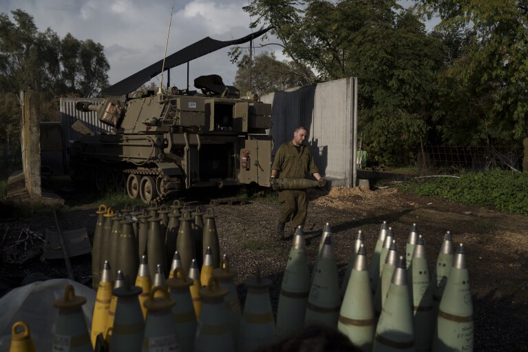 An Israeli soldier carries a howitzer shell near the border with Lebanon, in northern Israel, Thursday, Jan. 11, 2024. AP Photo/Leo Correa)