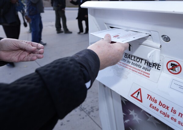 FILE - A voter places a ballot in a drop box outside the Denver Elections Division headquarters Nov. 8, 2022, in downtown Denver. The nation's cybersecurity agency is launching a program aimed at boosting election security in the states, shoring up support for local offices and hoping to provide reassurance to voters that this year's presidential elections will be safe and accurate. (AP Photo/David Zalubowski, File)