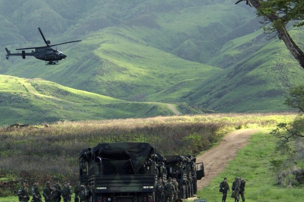 FILE - An Army Kiowa helicopter flies over a convoy of U.S. soldiers at the Makua Military Reservation in Hawaii, Dec. 8, 2003. In December 2023, the U.S. military confirmed that it will permanently end live-fire training in Makua Valley on Oahu, in a major win for Native Hawaiian groups and environmentalists after decades of activism. (AP Photo/Carol Cunningham, File)