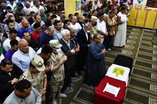 Hombres rezan frente al ataúd del militar Ahmed Mohamed Ahmed Ali, muerto en combate, durante su servicio fúnebre, el domingo 8 de mayo de 2022, en la provincia de Qalyubia, Egipto.  (AP Foto/Sayed Hassan)