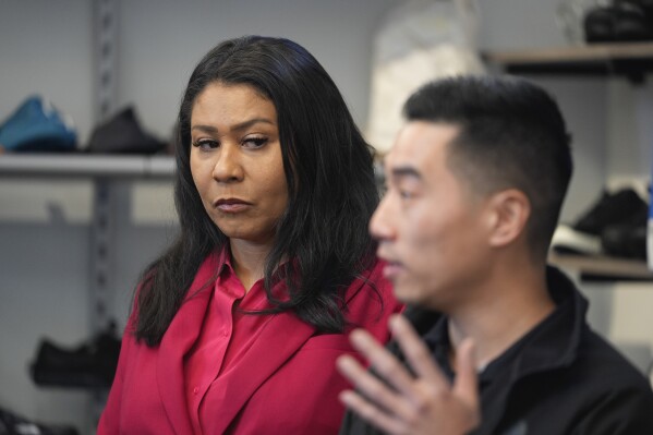 San Francisco Mayor London Breed, left, listens to store owner Mike Hsu speak about a recent burglary, during a news conference to promote a crime measure at the Footprint retail store in San Francisco, Thursday, Jan. 25, 2024. The Democratic mayor of San Francisco is pushing a pair of controversial public safety proposals on the March 5, ballot. Critics say the measures are out of step with San Francisco's liberal politics and will hurt already marginalized communities. (AP Photo/Eric Risberg)