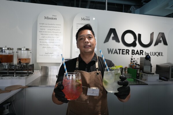 JC, mixologist, presents two types of gourmet water cocktails at the AQUA Water Bar by LUQEL in Dubai, United Arab Emirates, Tuesday, July 11, 2023. Dubai's gourmet water bar joins a growing list of unique businesses that have sprouted out of the uninterrupted stretches of windblown sand dunes turned into a bustling desert metropolis, complete with the world's tallest building, cavernous malls, and palm-shaped man-made islands. (AP Photo/Kamran Jebreili)