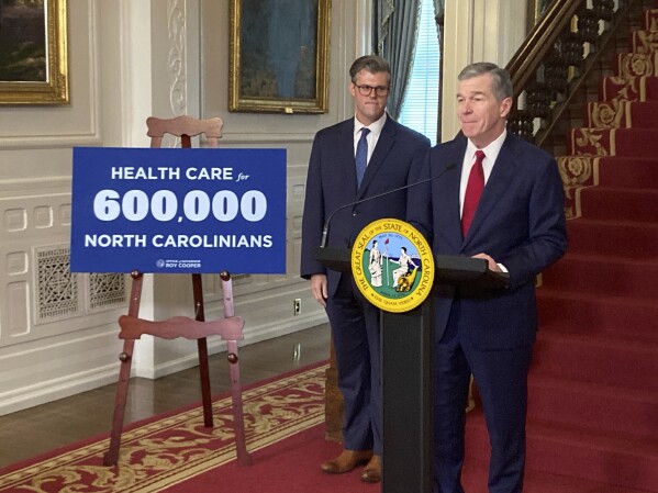 North Carolina Gov. Roy Cooper, right, speaks while state Health and Human Services Secretary Kody Kinsley listens at an Executive Mansion news conference in Raleigh, N.C., on Monday, Sept. 25, 2023. Cooper and Kinsley announced that North Carolina would launch Medicaid expansion coverage on Dec. 1. Expansion will be able to start because Cooper said he'll let a state budget bill sent by the General Assembly last week to his desk become law without his signature. (AP Photo/Gary D. Robertson)