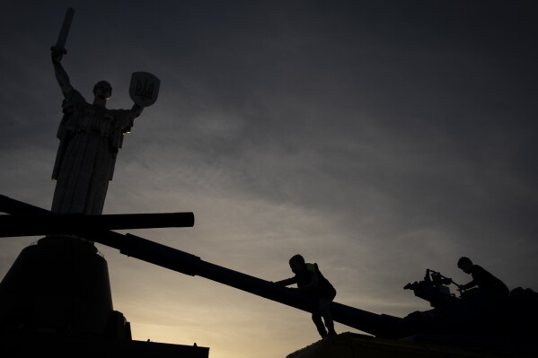 Children play on top of tanks on display in front of the Motherland Monument in Kyiv, Ukraine, Tuesday, Oct. 31, 2023. (AP Photo/Bram Janssen)