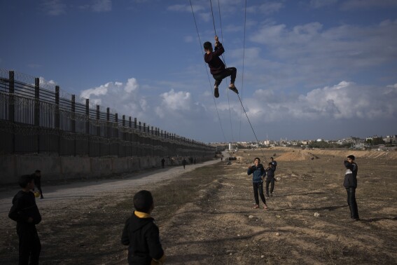 FILE - Palestinians displaced by the Israeli bombardment of the northern Gaza Strip play next to the border with Egypt, in Rafah, along the Philadelphi corridor, southern Gaza, Sunday, Jan. 14, 2024. (AP Photo/Fatima Shbair, File)