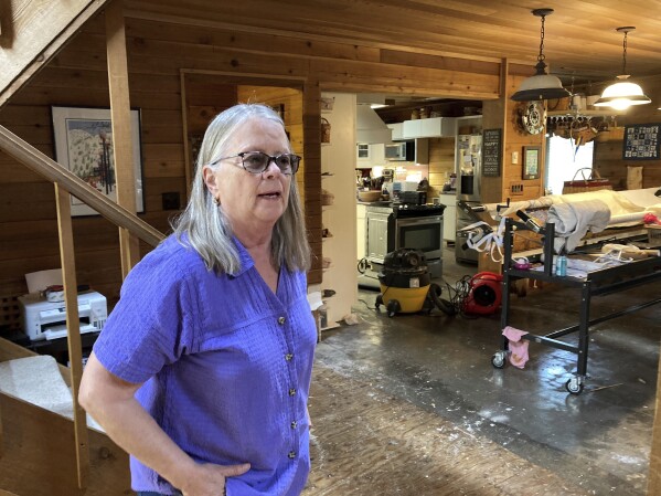 Chris Winter stands in her home in Juneau, Alaska, on Monday, Aug. 7, 2023, after a weekend glacial lake outburst flood resulted in about three inches of water in the raised home, which damaged flooring and insulation. City officials said water levels had returned to normal Monday but that banks along the river remained unstable. (AP Photo/Becky Bohrer)