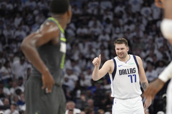 Dallas Mavericks guard Luka Doncic (77) celebrates his score as Minnesota Timberwolves guard Anthony Edwards, left, looks on during the first half of Game 5 of the Western Conference finals in the NBA basketball playoffs, Thursday, May 30, 2024, in Minneapolis. (AP Photo/Abbie Parr)