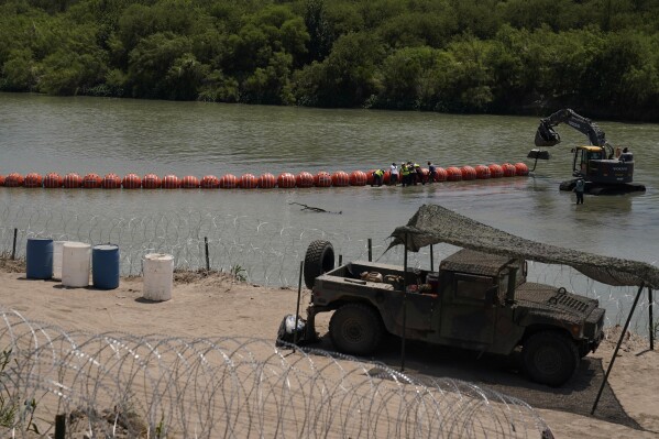 Workers assemble large buoys to be used as a border barrier along the banks of the Rio Grande in Eagle Pass, Texas, Tuesday, July 11, 2023. Texas Republican Gov. Greg Abbott has escalated measures to keep migrants from entering the U.S. He's pushing legal boundaries along the border with Mexico to install razor wire, deploy massive buoys on the Rio Grande and bulldozing border islands in the river. (AP Photo/Eric Gay)