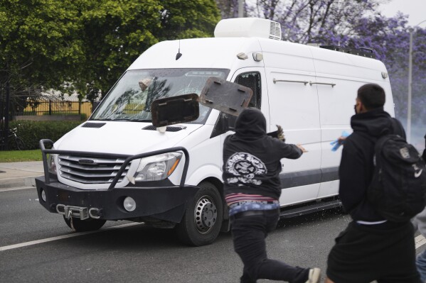 Protesters throw objects as law enforcement drive a van past during a protest in the Paramount section of Los Angeles, Saturday, June 7, 2025, after federal immigration authorities conducted operations. (AP Photo/Eric Thayer)