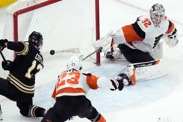 Boston Bruins' Charlie Coyle (13) scores on Philadelphia Flyers' Felix Sandstrom (32) during the second period of an NHL hockey game, Saturday, March 16, 2024, in Boston. (AP Photo/Michael Dwyer)