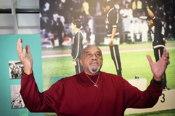 American former track and field athlete Tommie Smith gestures in front of the photograph of him at the 1968 Olympics, at the Immigration Museum, Tuesday, June 11, 2024 in Paris. Smith and John Carlos gave a black-gloved salute on the medal stand at the 1968 Olympics in Mexico City. (AP Photo/Thomas Padilla)