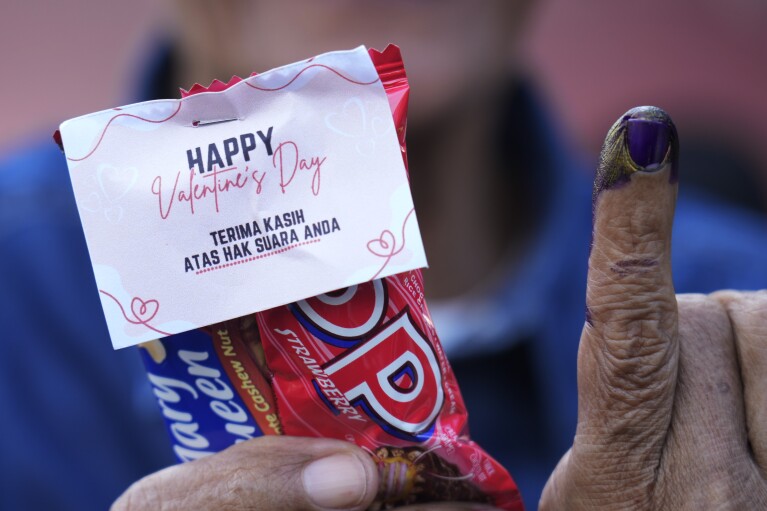 A man shows his finger inked to mark that he has already voted during the election at a Valentine's Day-themed polling station during the election in Solo, Central Java, Indonesia, Wednesday, Feb. 14, 2024. (AP Photo/Achmad Ibrahim)