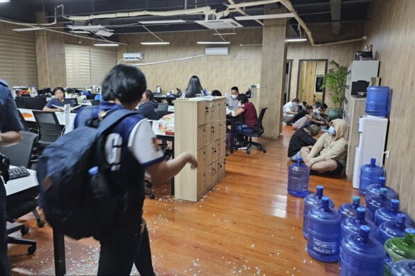 In this handout photo provided by the Philippine National Police Anti-Cybercrime Group, police walks inside one of the offices they raided in Las Pinas, Philippines on Tuesday June 27, 2023. Philippine police backed by commandos staged a massive raid on Tuesday and said they rescued more than 2,700 workers from China, the Philippines, Vietnam, Indonesia and more than a dozen other countries who were allegedly swindled into working for fraudulent online gaming sites and other cybercrime groups. (Philippine National Police Anti-Cybercrime Group via AP)