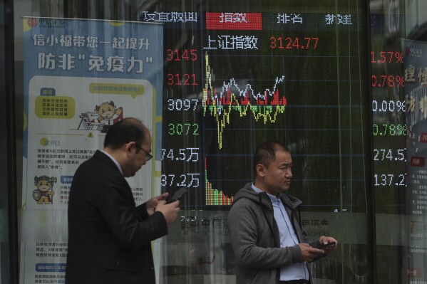 People pass in front of an electronic card displaying the trading index of shanghai actions in a brokerage house in Beijing, Tuesday April 8, 2025. (AP photo / Andy Wong)