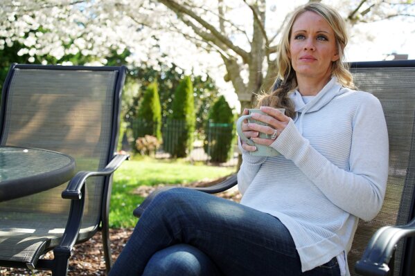 
              In this Wednesday, March 27, 2019, photo, Kacey Ruegsegger Johnson enjoys a coffee in a light spring breeze in the back yard of her home in Cary, N.C. For the last 20 years since she was injured in the Columbine High School attack, she has lived with post-traumatic stress disorder, along with physical pain.  Now a mother of four, she has worked hard not to pass that fear on to her children. (AP Photo/Allen G. Breed)
            