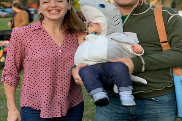 
              This image released by Jason Simms shows him with his wife Jillian and their daughter Fionnuala wearing a shark costume on the Town Green in Madison, Conn.  Fionnuala first heard the "Baby Shark" song when she was 8 months old. Her parents say it was one of the first things in life she directly expressed a preference for, so they picked it for her Halloween costume. (Jason Simms via AP)
            