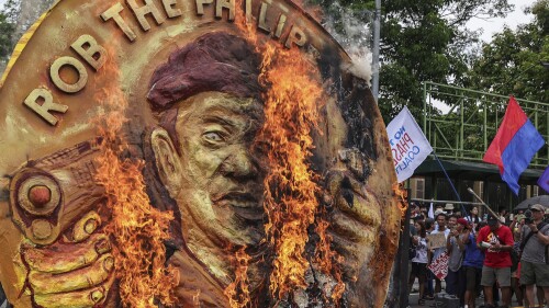 Protesters burn a two-faced gold coin effigy of President Ferdinand Marcos during a rally in Quezon City, Philippines, Monday, July 24, 2023, ahead of the second State of the Nation Address of Philippine President Ferdinand Marcos Jr. (AP Photo/Gerard Carreon)