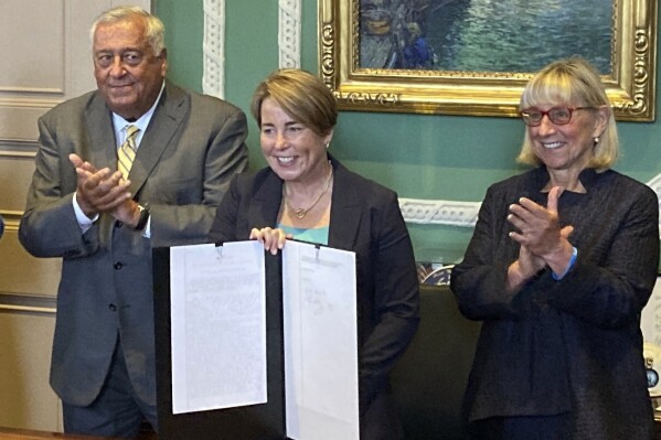 Massachusetts Gov. Maura Healey, center, shows the signed a nearly $58 billion state budget bill Monday, July 29, 2024, in Boston, that includes a plan for free community college and allows the Massachusetts Lottery to move some of its products online. Healey is flanked by Massachusetts House Speaker Ronald Mariano, left, and Senate President Karen Spilka. (AP Photo/Steve LeBlanc)