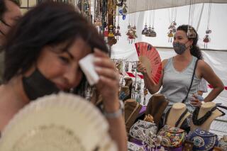 FILE - Women cool themselves with fans in the Rastro flea market during a heatwave in Madrid, Spain, Aug. 15, 2021. Scientists say last summer was the hottest summer on record in Europe, with temperatures a 1.8 Fahrenheit higher than the average for the previous three decades. A report released Friday, April 22, 2022 by the European Union’s Copernicus Climate Change Service found that while spring 2021 was cooler than average, the summer months were marked by “severe and long-lasting heatwaves.” (AP Photo/Andrea Comas, file)