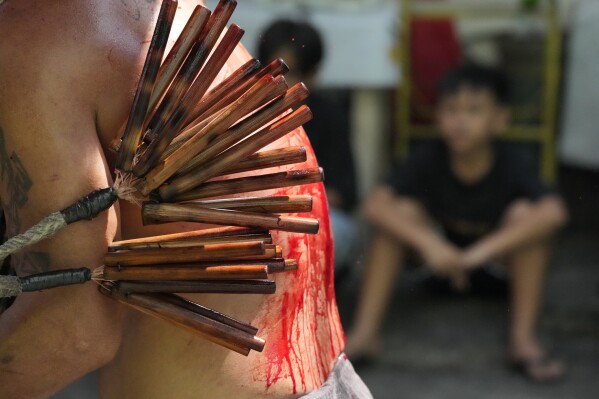 A hooded Filipino penitent flagellates himself as part of Holy Week rituals to atone for sins or fulfill vows for an answered prayer in metropolitan Manila, Philippines on Maundy Thursday, March 28, 2024. (AP Photo/Aaron Favila)