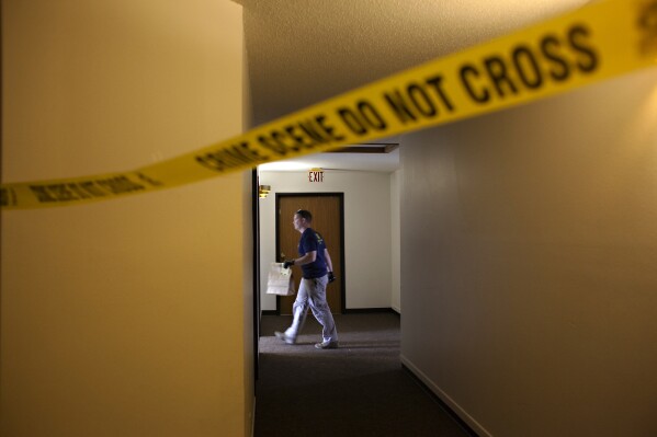 An FBI Evidence Response Team investigator walks behind crime scene tape on the third floor of the Bluemont Village Apartments, Saturday, July 15, 2023, in Fargo, N.D. The suspect in a fatal shooting involving police officers a day earlier was connected to at least one apartment unit at this location. Both the suspect and one police officer were killed. (AP Photo/Ann Arbor Miller)